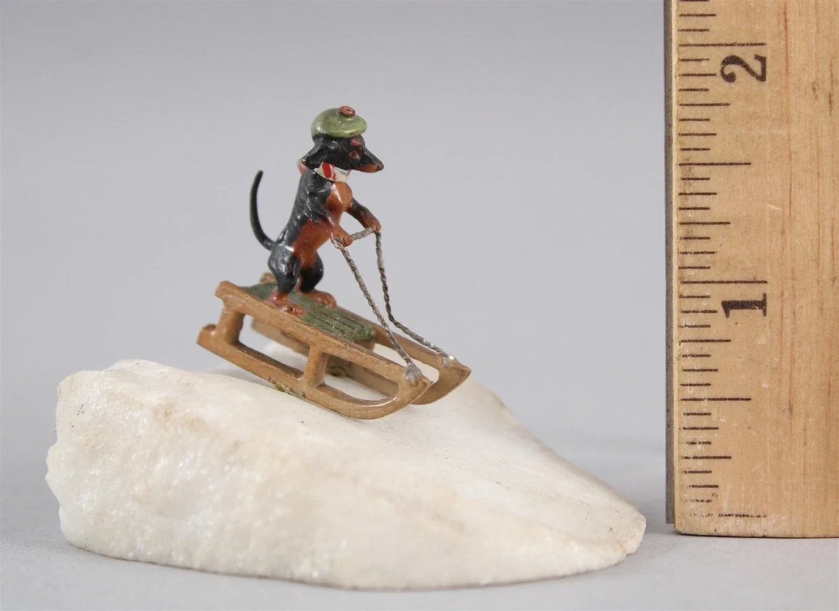 Antique Austrian miniature bronze sculpture depicting a dachshund sledding in the snow.