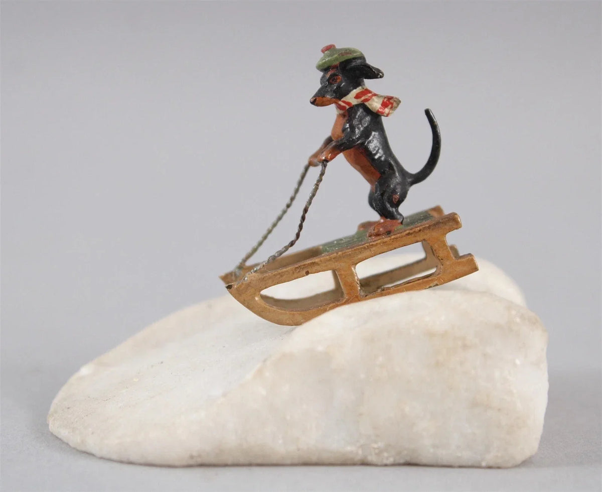 Antique Austrian miniature bronze sculpture depicting a dachshund sledding in the snow.