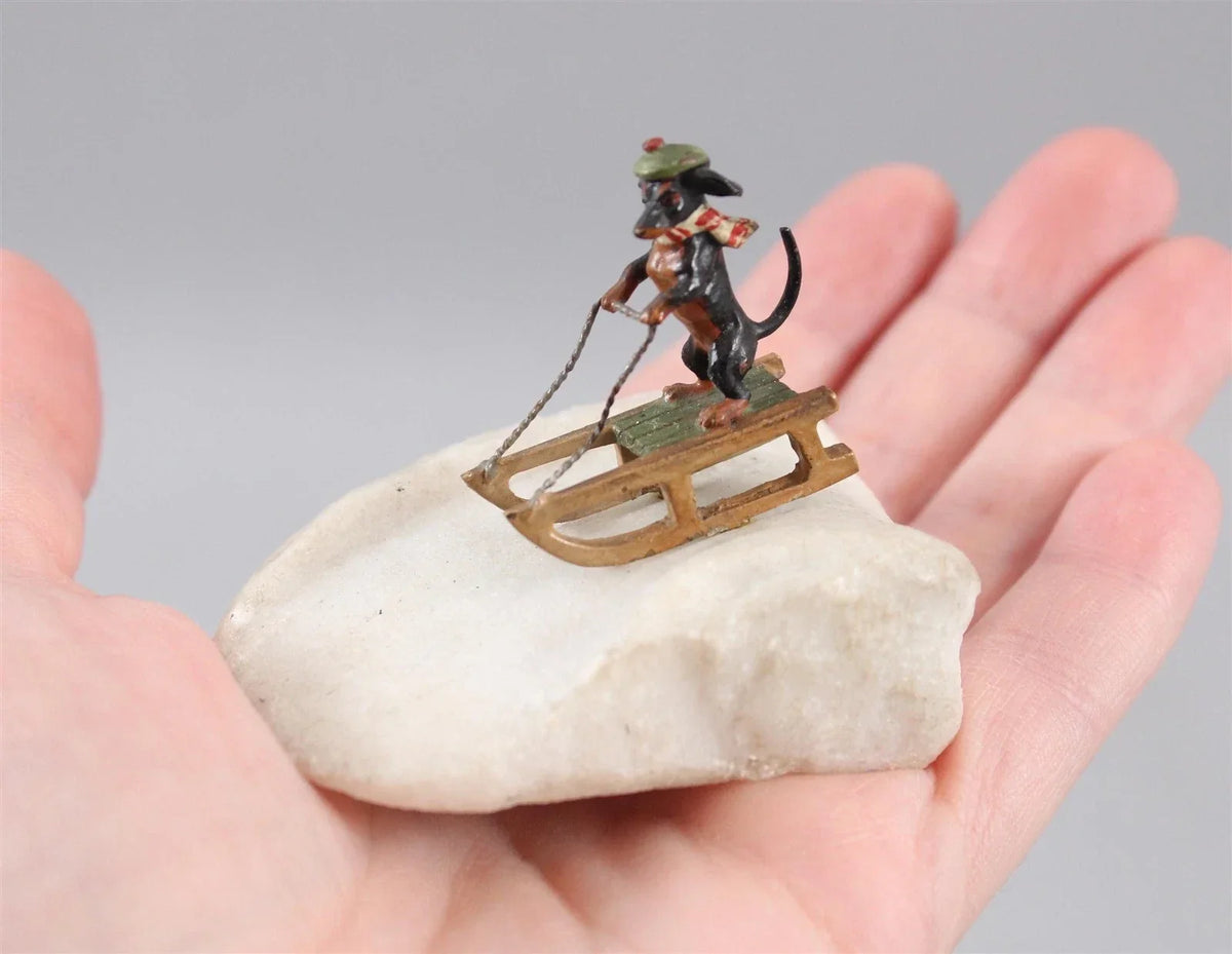Antique Austrian miniature bronze sculpture depicting a dachshund sledding in the snow.